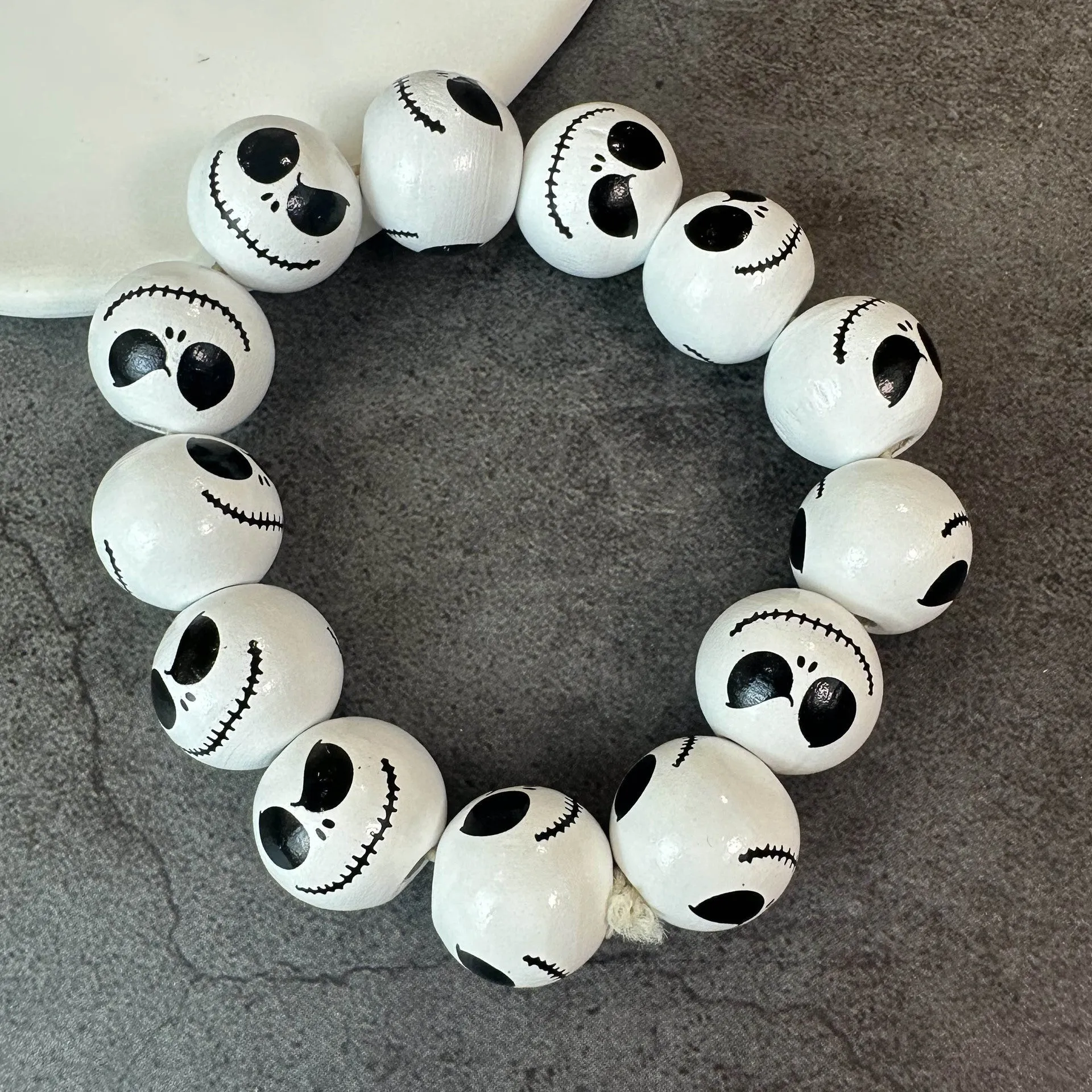 Handmade wooden bead Halloween jewellery set with ghost face, pumpkin, and skull motifs on a dark background.