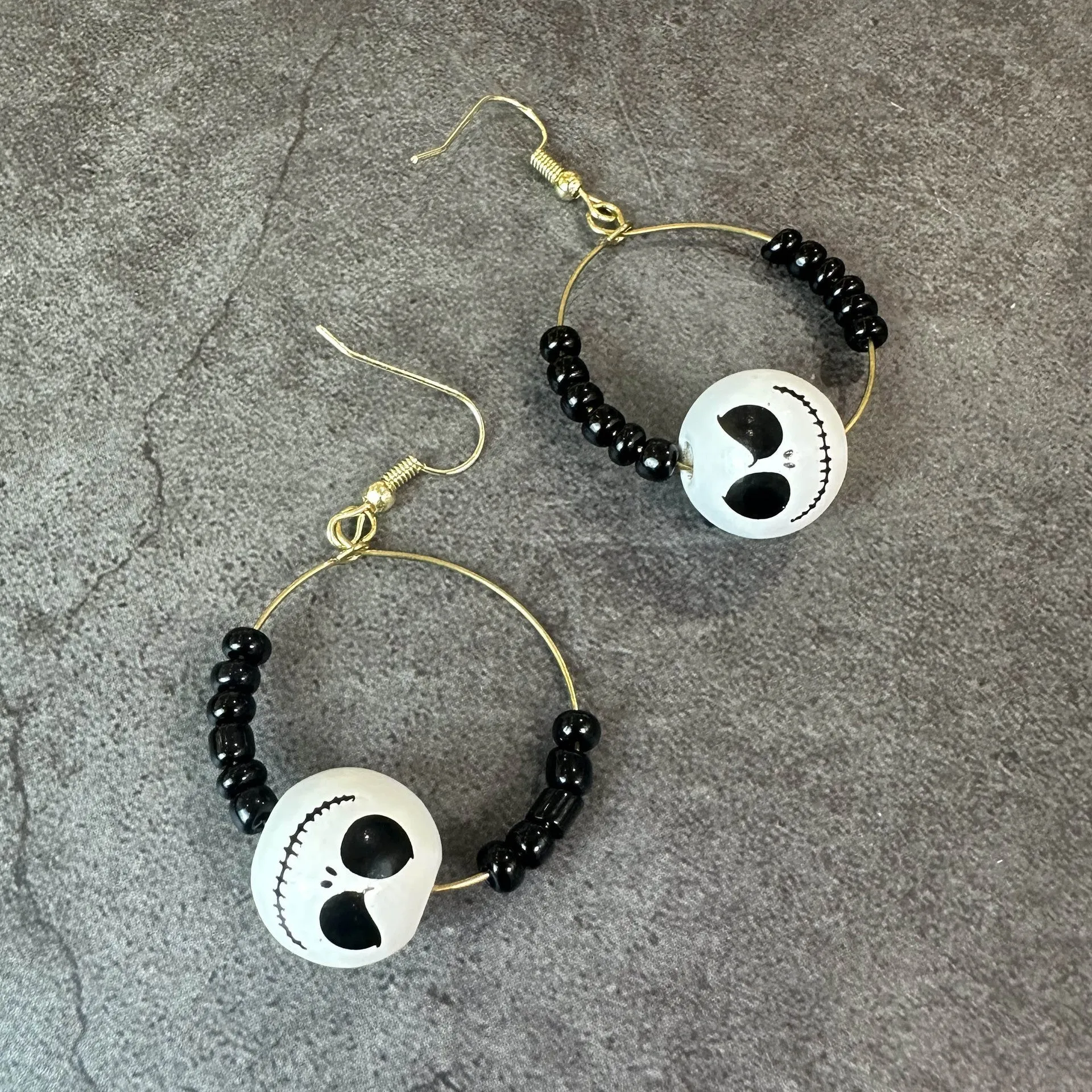 Handmade wooden bead Halloween jewellery set with ghost face, pumpkin, and skull motifs on a dark background.