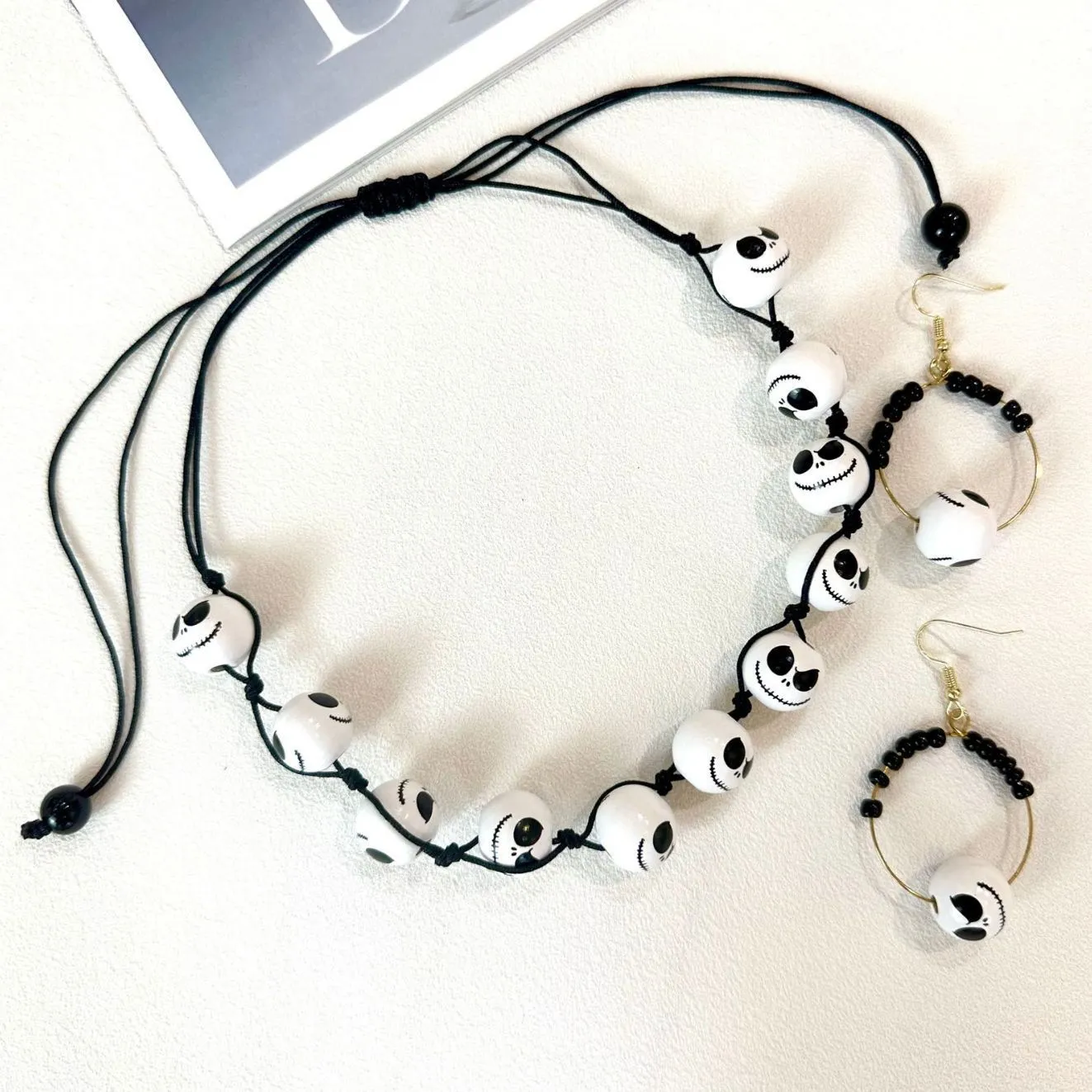 Handmade wooden bead Halloween jewellery set with ghost face, pumpkin, and skull motifs on a dark background.
