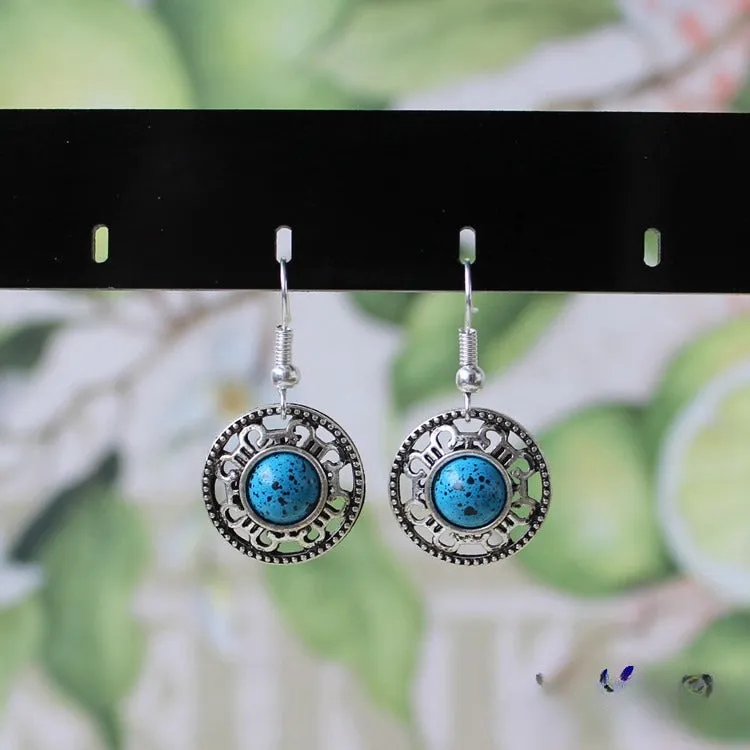 Handmade silver and turquoise ethnic earrings with geometric flower disk and traditional patterns.
