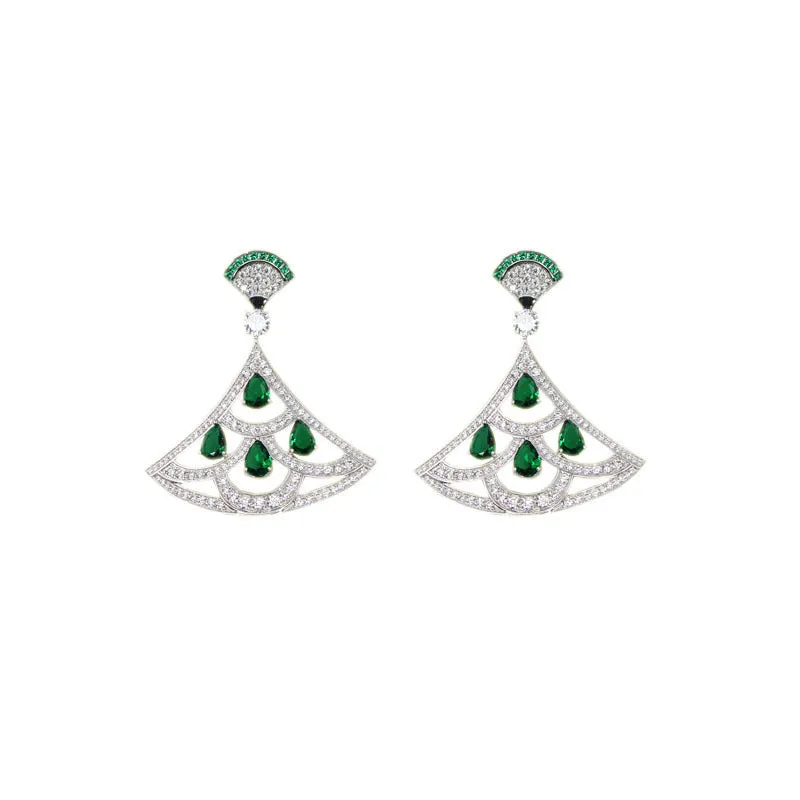 Silver fan-shaped earring with gold-plated inlay of artificial gems, on a plain background