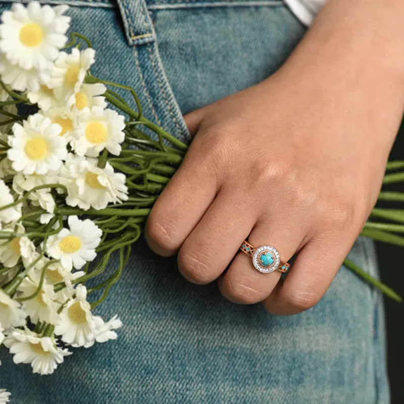 Rose gold women's ring with turquoise geometric centre and inlaid zircon stones on a finger.