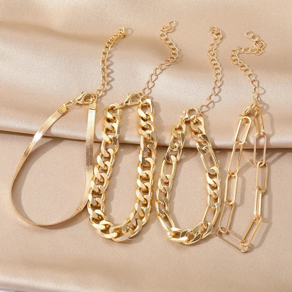 Set of four gold electroplated alloy bracelets on a surface