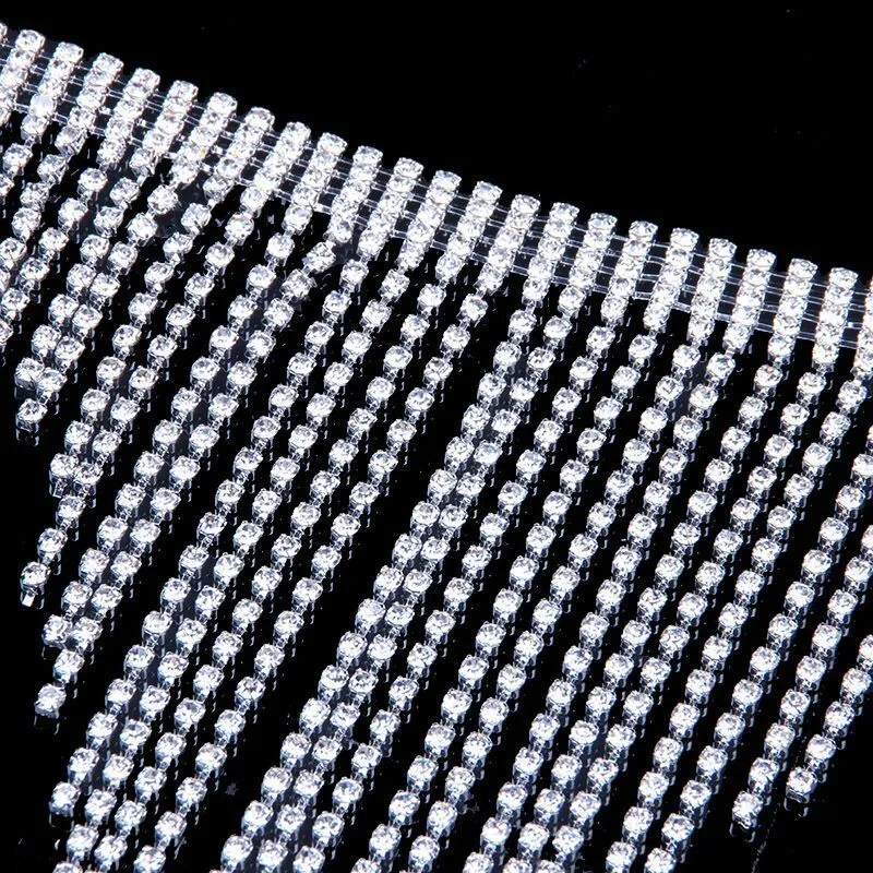 Silvery rhinestone body chain laid flat on a white surface showing metal links and clear stones