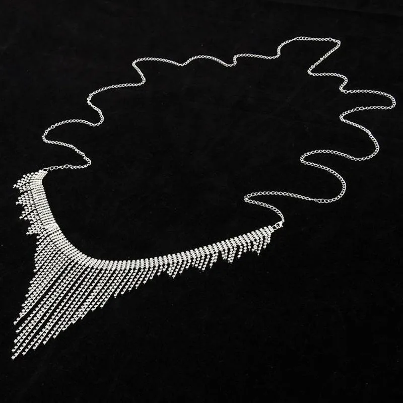 Silvery rhinestone body chain laid flat on a white surface showing metal links and clear stones