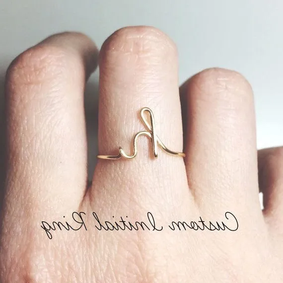Gold coloured unisex alloy initial ring with letter A geometric shape on a flat surface