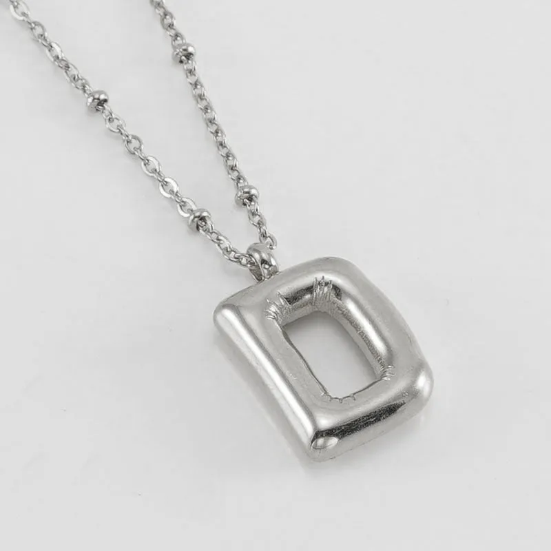 Gold bubble letter N pendant on stainless steel clip beads chain necklace against white background