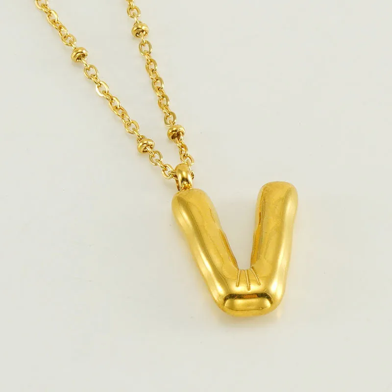 Gold bubble letter N pendant on stainless steel clip beads chain necklace against white background