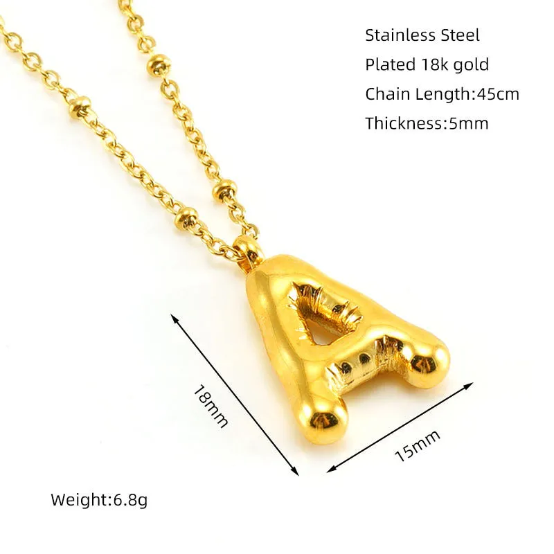 Gold bubble letter N pendant on stainless steel clip beads chain necklace against white background