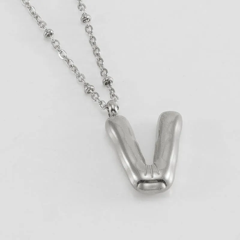 Gold bubble letter N pendant on stainless steel clip beads chain necklace against white background