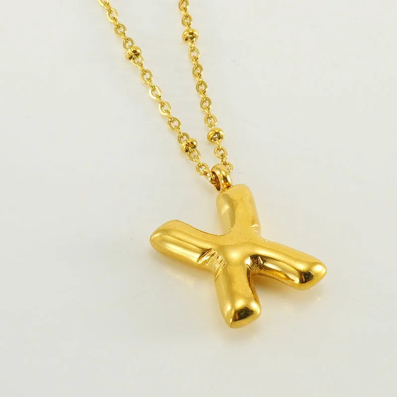 Gold bubble letter N pendant on stainless steel clip beads chain necklace against white background
