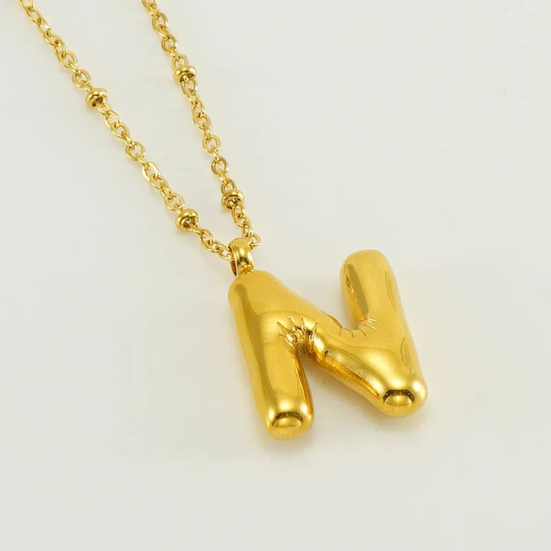 Gold bubble letter N pendant on stainless steel clip beads chain necklace against white background