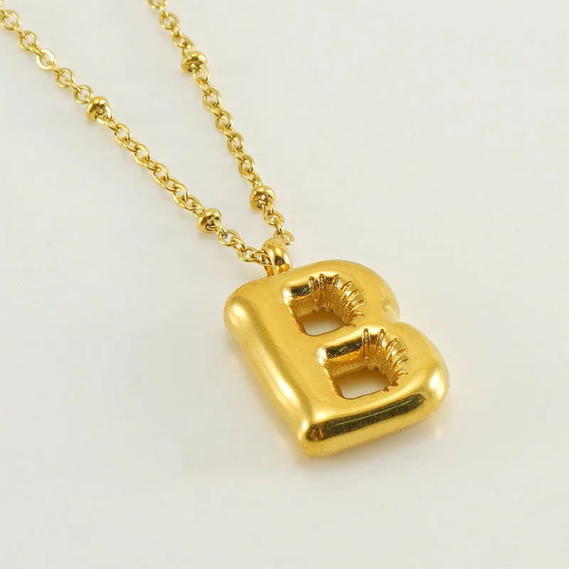 Gold bubble letter N pendant on stainless steel clip beads chain necklace against white background
