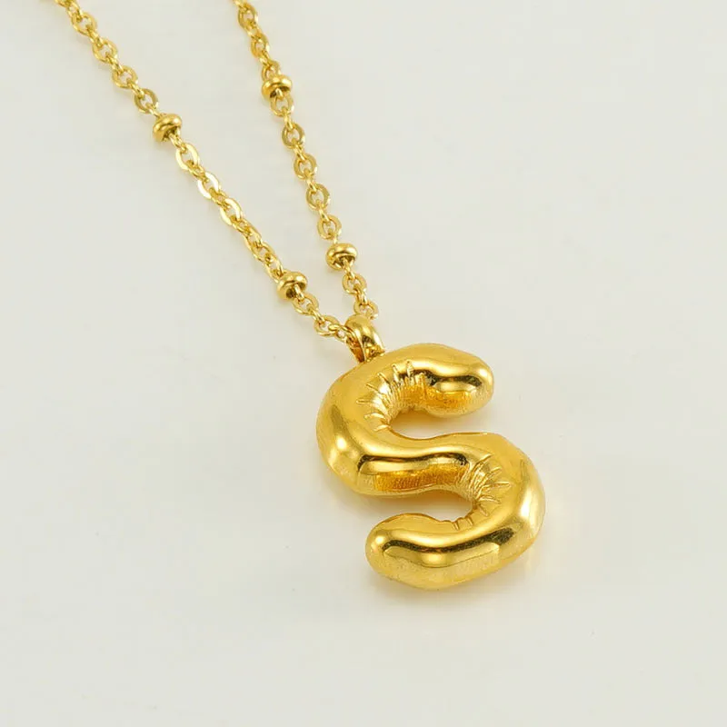 Gold bubble letter N pendant on stainless steel clip beads chain necklace against white background