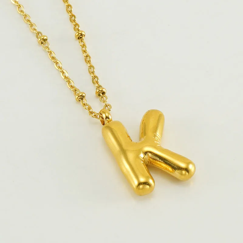 Gold bubble letter N pendant on stainless steel clip beads chain necklace against white background