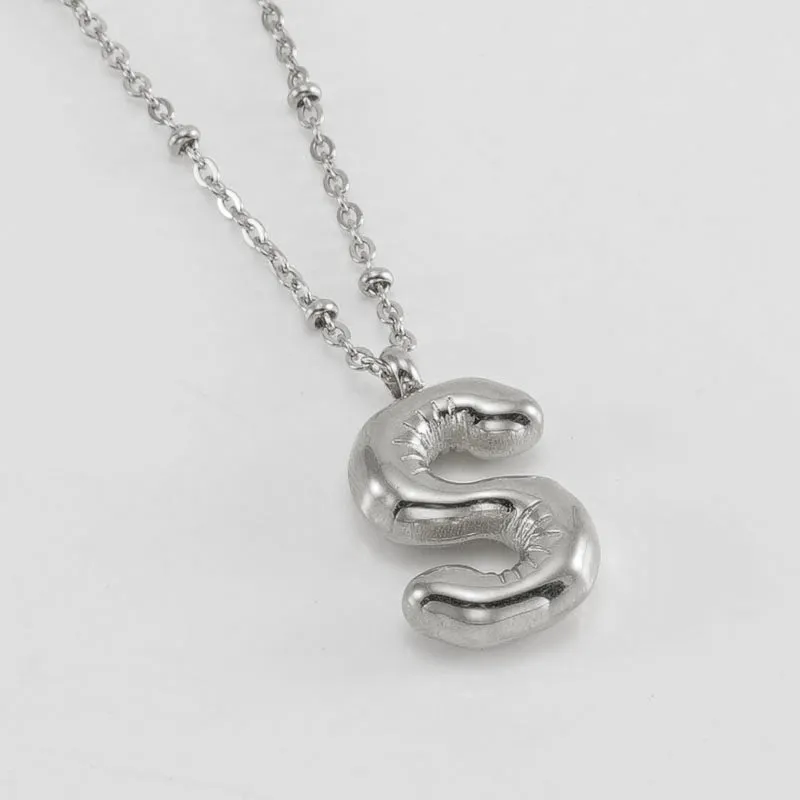 Gold bubble letter N pendant on stainless steel clip beads chain necklace against white background