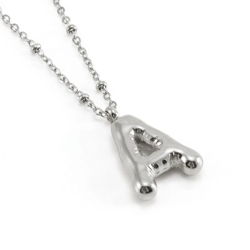 Gold bubble letter N pendant on stainless steel clip beads chain necklace against white background