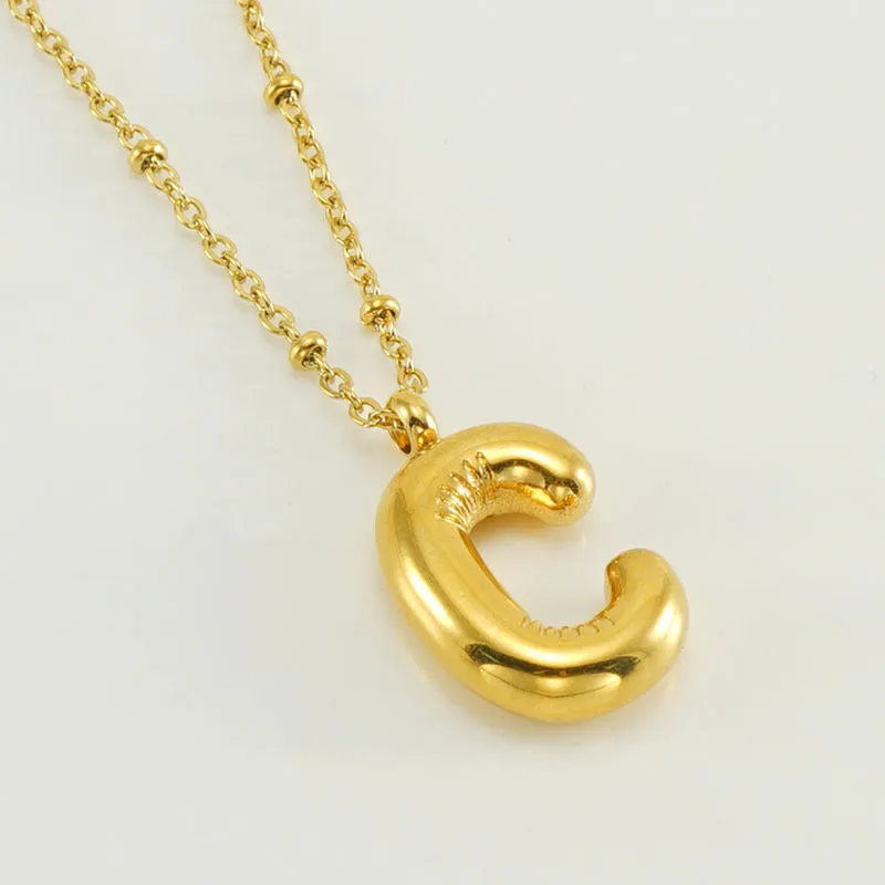 Gold bubble letter N pendant on stainless steel clip beads chain necklace against white background