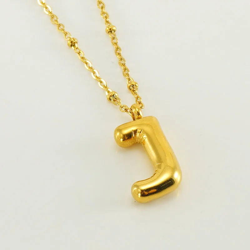 Gold bubble letter N pendant on stainless steel clip beads chain necklace against white background