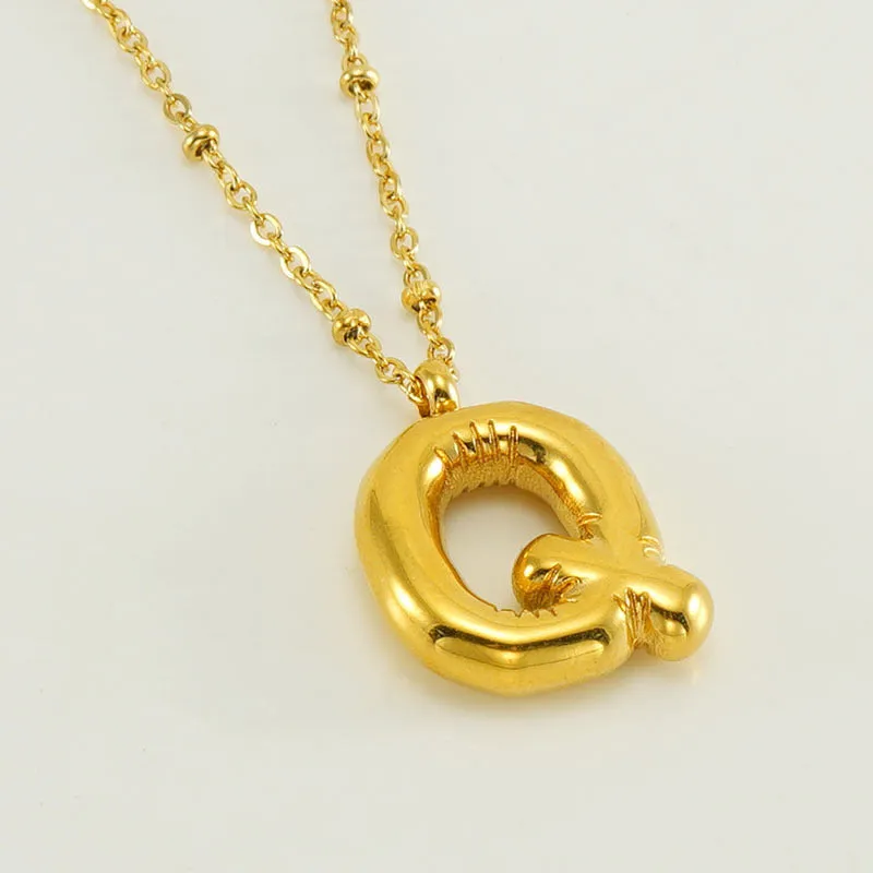 Gold bubble letter N pendant on stainless steel clip beads chain necklace against white background