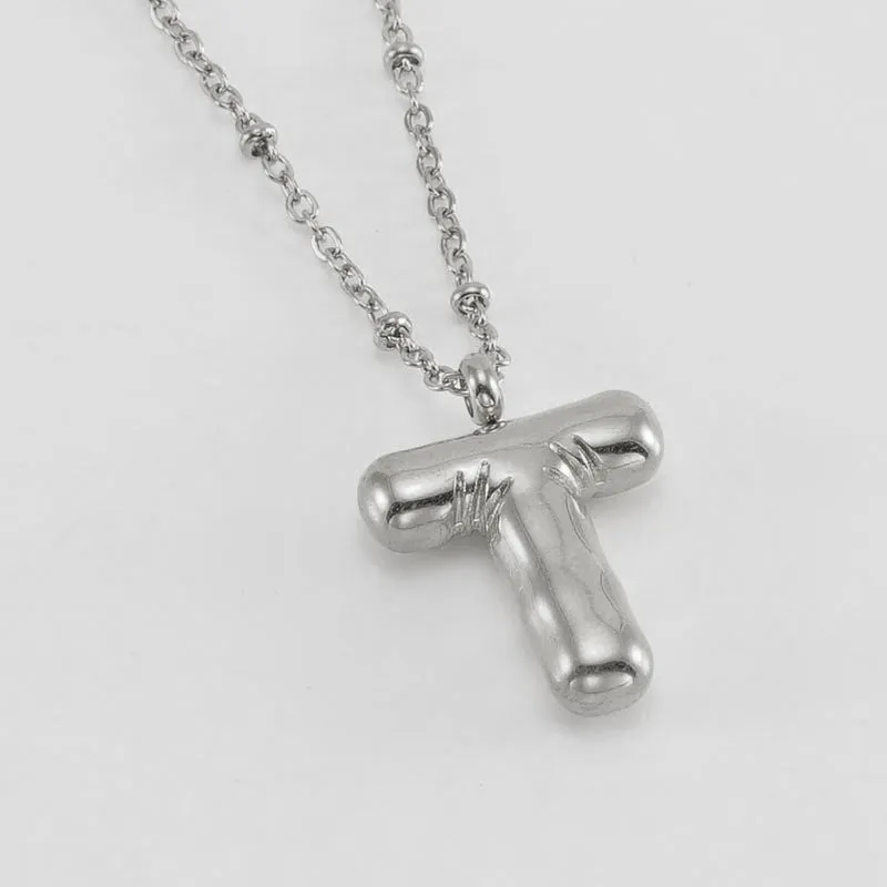 Gold bubble letter N pendant on stainless steel clip beads chain necklace against white background
