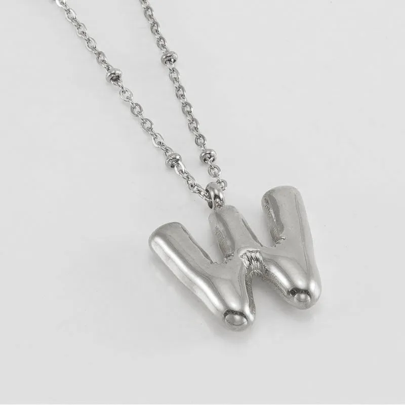Gold bubble letter N pendant on stainless steel clip beads chain necklace against white background