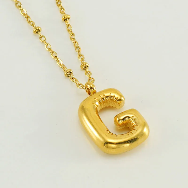 Gold bubble letter N pendant on stainless steel clip beads chain necklace against white background