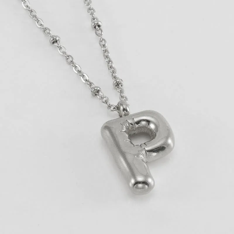 Gold bubble letter N pendant on stainless steel clip beads chain necklace against white background