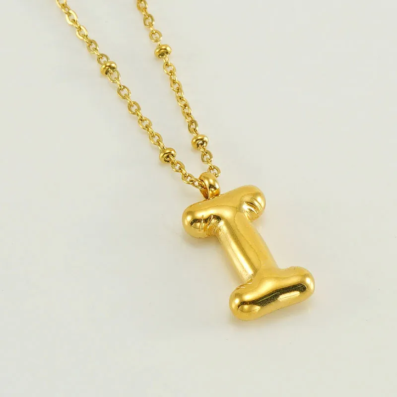 Gold bubble letter N pendant on stainless steel clip beads chain necklace against white background