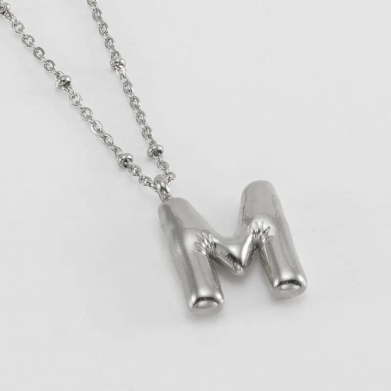 Gold bubble letter N pendant on stainless steel clip beads chain necklace against white background