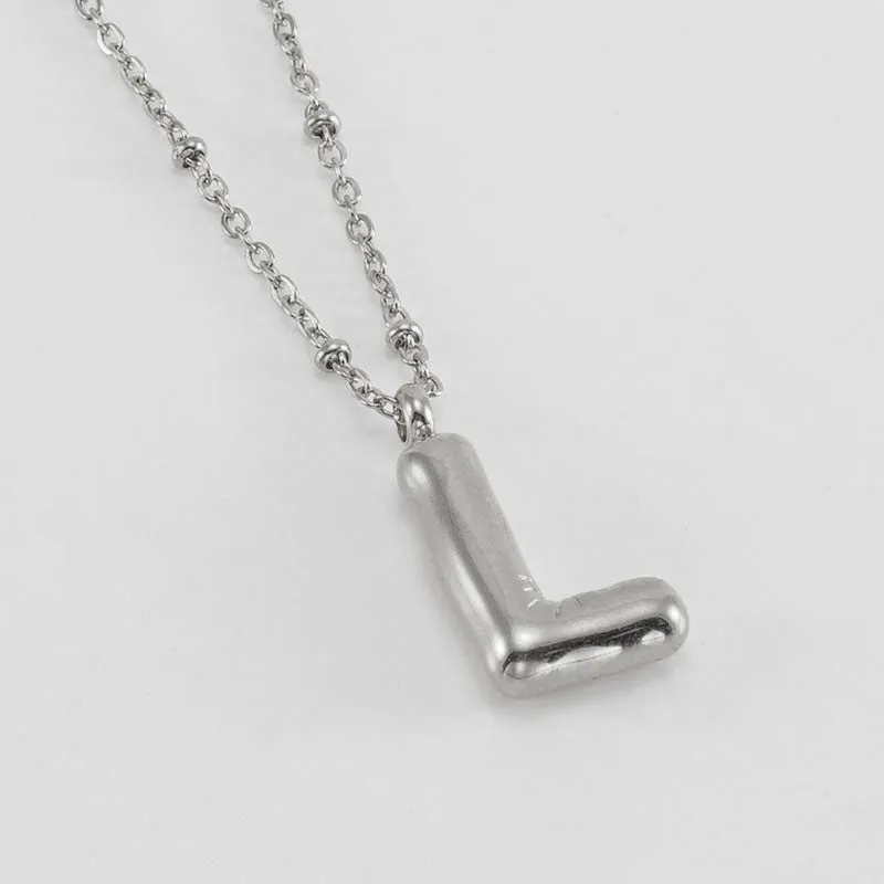 Gold bubble letter N pendant on stainless steel clip beads chain necklace against white background