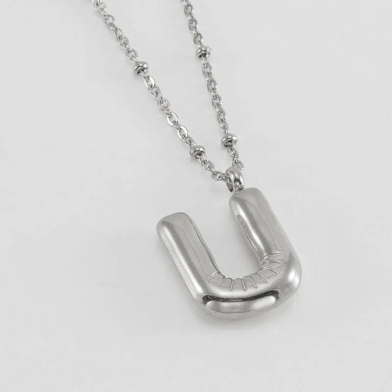 Gold bubble letter N pendant on stainless steel clip beads chain necklace against white background