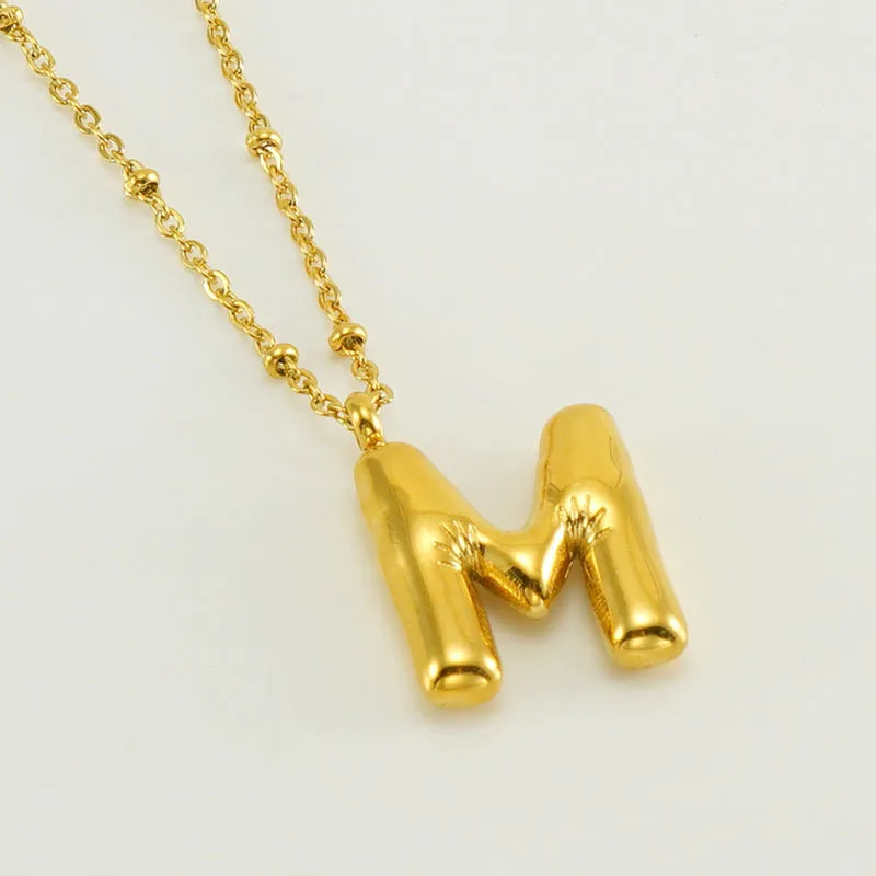 Gold bubble letter N pendant on stainless steel clip beads chain necklace against white background