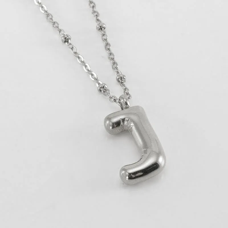 Gold bubble letter N pendant on stainless steel clip beads chain necklace against white background