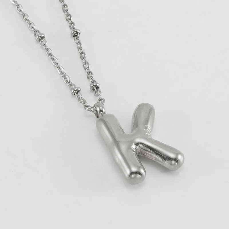 Gold bubble letter N pendant on stainless steel clip beads chain necklace against white background
