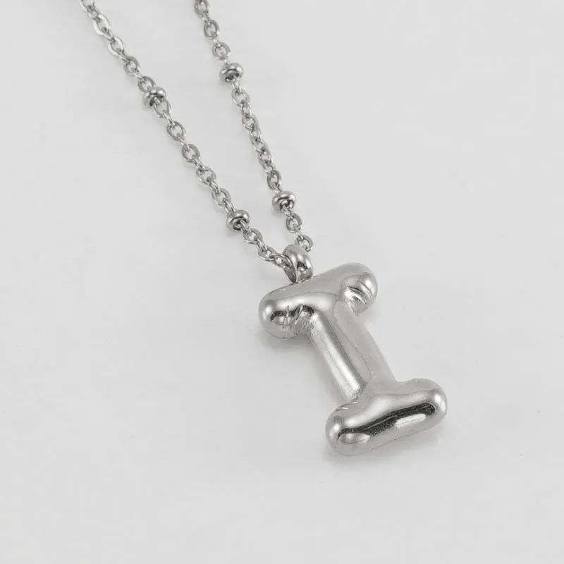 Gold bubble letter N pendant on stainless steel clip beads chain necklace against white background