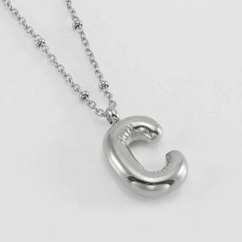 Gold bubble letter N pendant on stainless steel clip beads chain necklace against white background