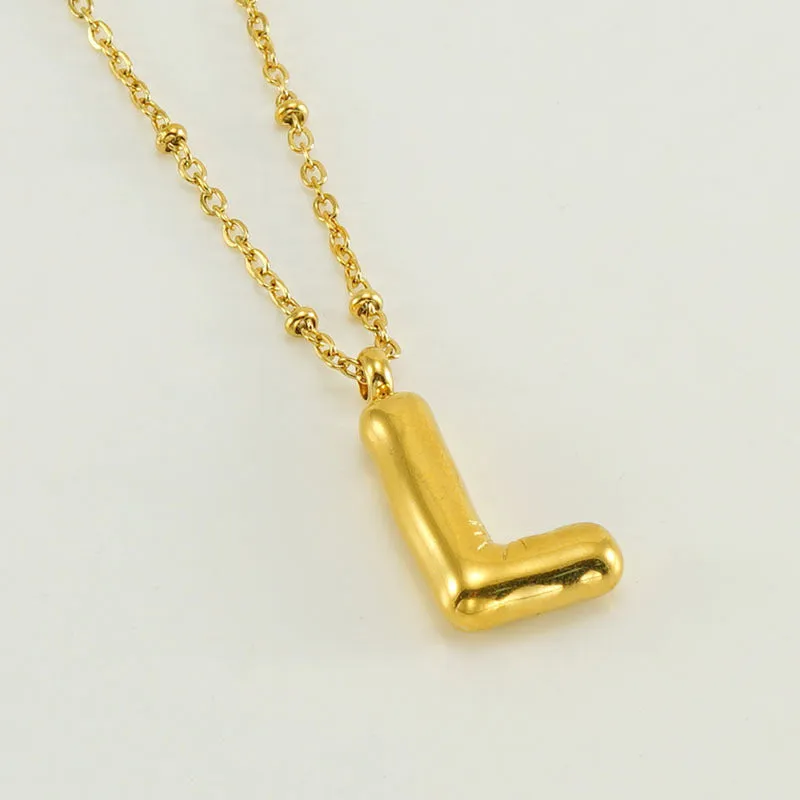 Gold bubble letter N pendant on stainless steel clip beads chain necklace against white background