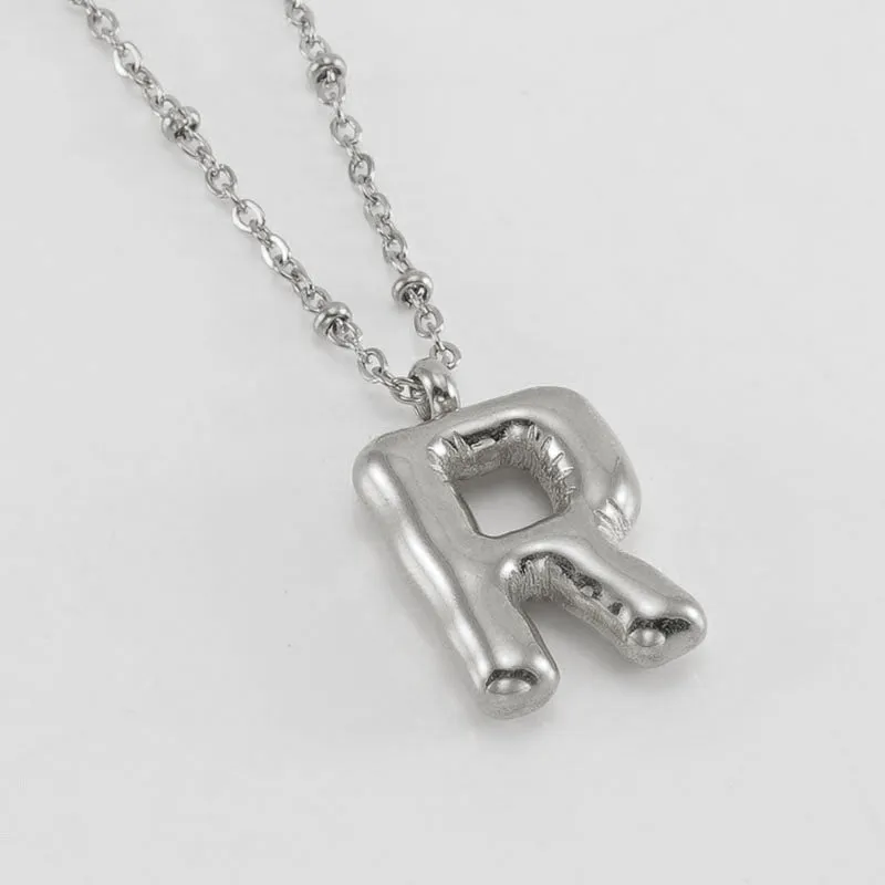 Gold bubble letter N pendant on stainless steel clip beads chain necklace against white background