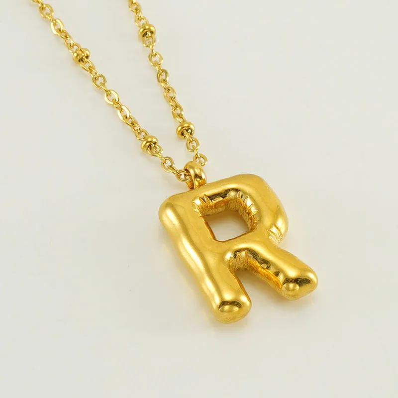 Gold bubble letter N pendant on stainless steel clip beads chain necklace against white background