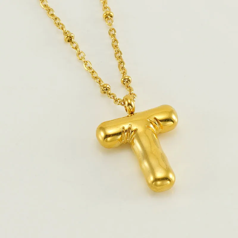 Gold bubble letter N pendant on stainless steel clip beads chain necklace against white background