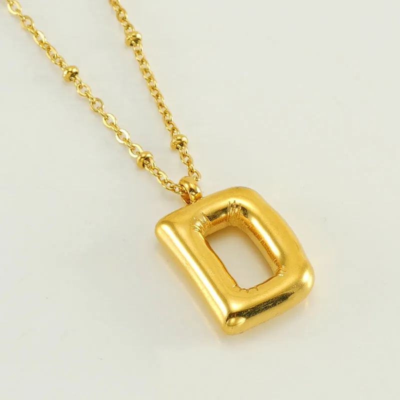 Gold bubble letter N pendant on stainless steel clip beads chain necklace against white background
