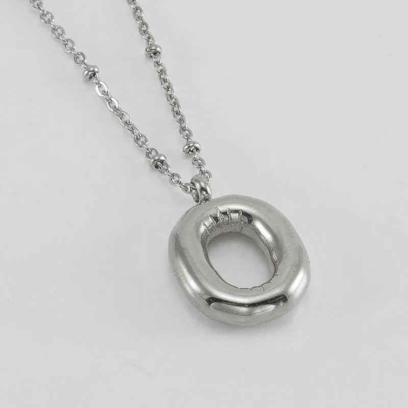 Gold bubble letter N pendant on stainless steel clip beads chain necklace against white background