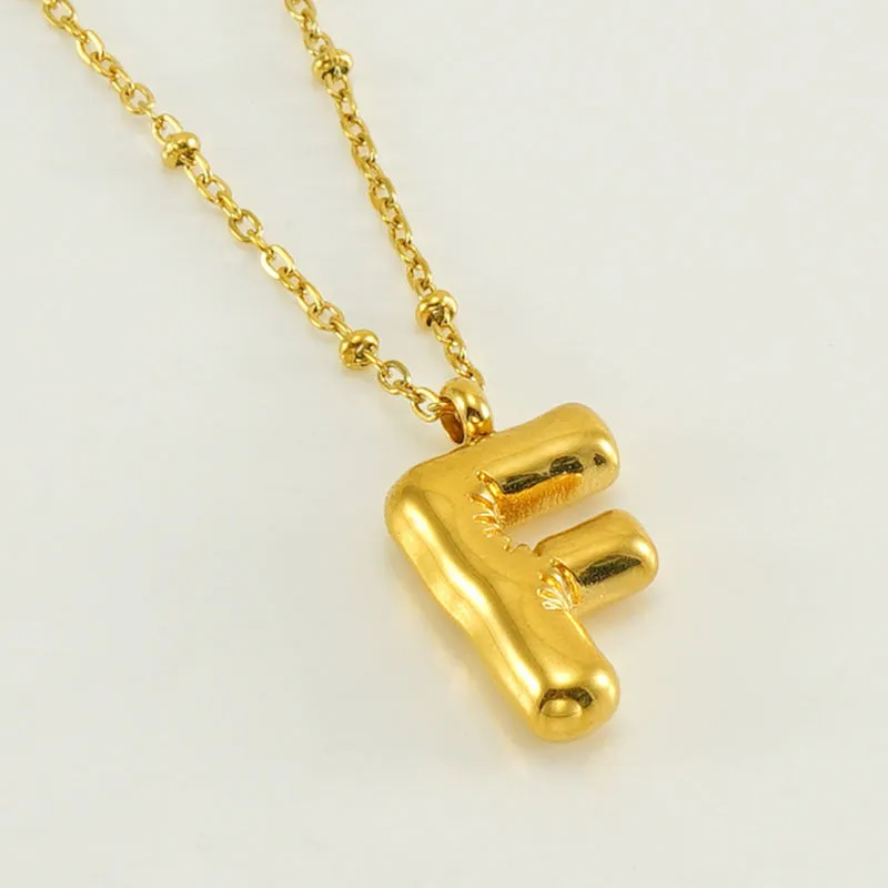 Gold bubble letter N pendant on stainless steel clip beads chain necklace against white background