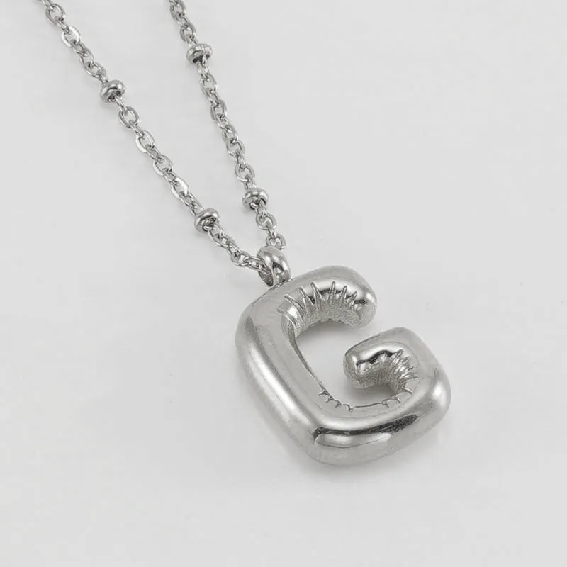 Gold bubble letter N pendant on stainless steel clip beads chain necklace against white background