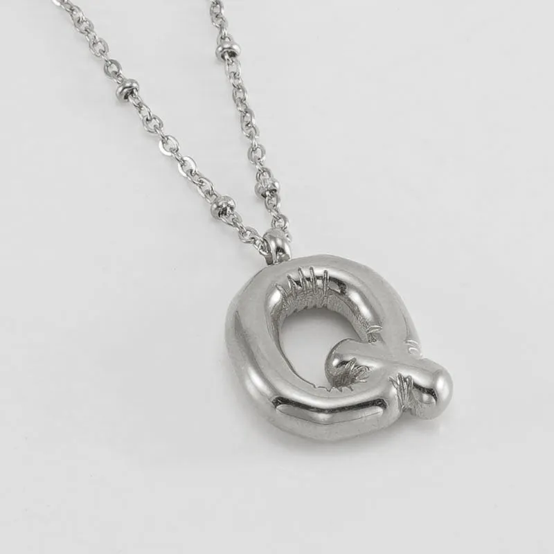 Gold bubble letter N pendant on stainless steel clip beads chain necklace against white background
