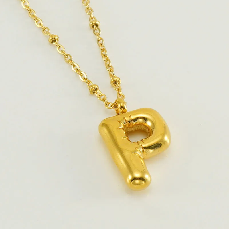 Gold bubble letter N pendant on stainless steel clip beads chain necklace against white background