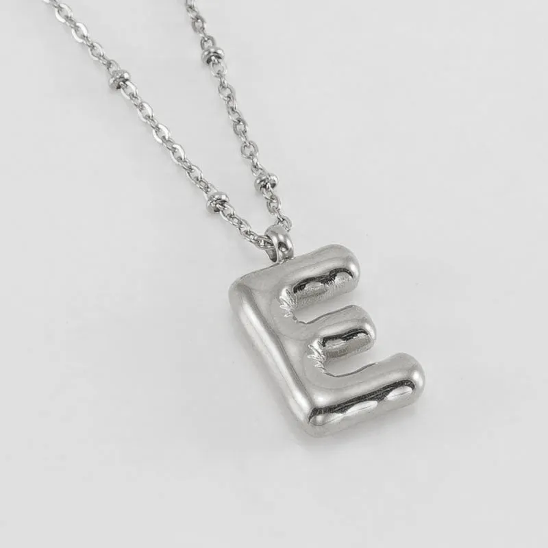 Gold bubble letter N pendant on stainless steel clip beads chain necklace against white background