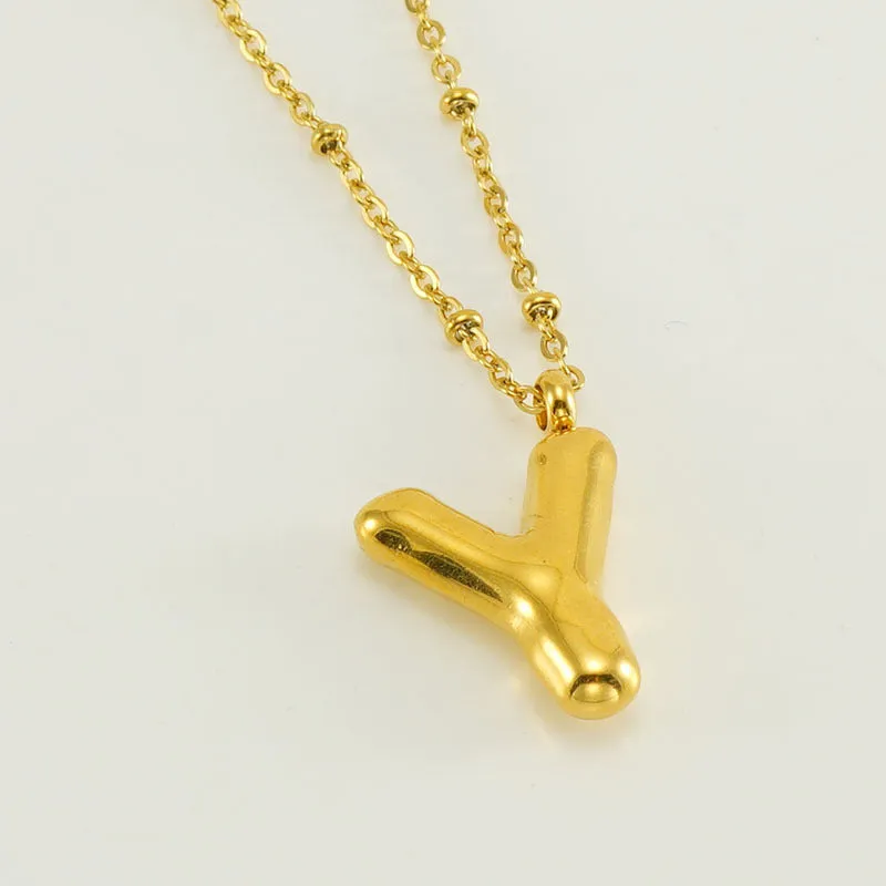 Gold bubble letter N pendant on stainless steel clip beads chain necklace against white background