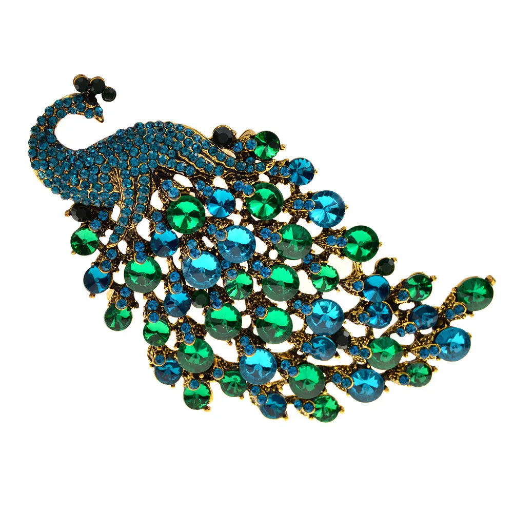 Colourful metal peacock brooch in red, green, and blue with rhinestone accents on a white background